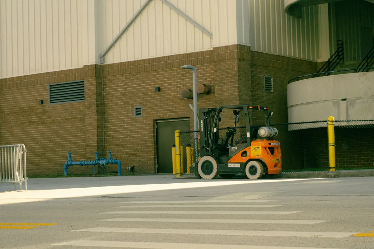 Orangefarbener Gabelstapler vor einer Industriehalle