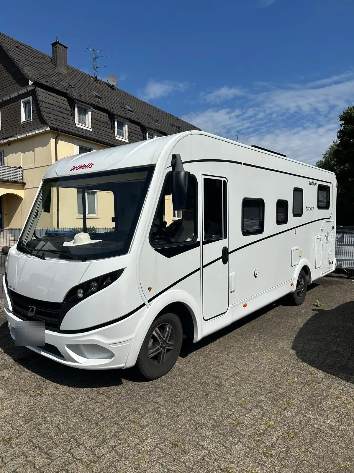 Weißes Dethleffs-Wohnmobil (Modell Trend) auf einem gepflasterten Stellplatz, von vorn schräg
